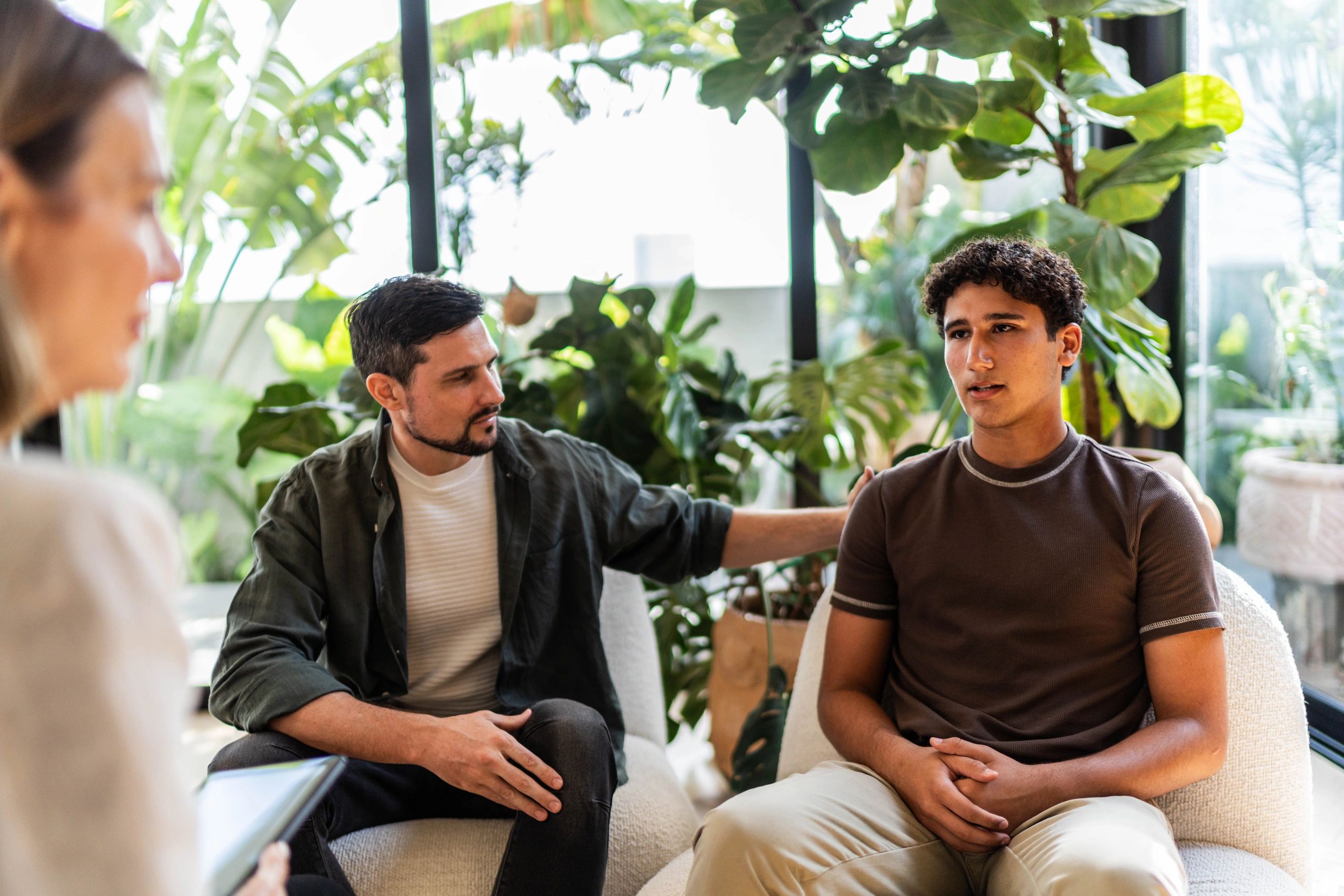 Parent and child speaking with a therapist in a supportive setting